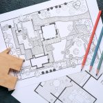 Backyard design process shown through detailed landscape plans, colored pencils, and a wooden house model